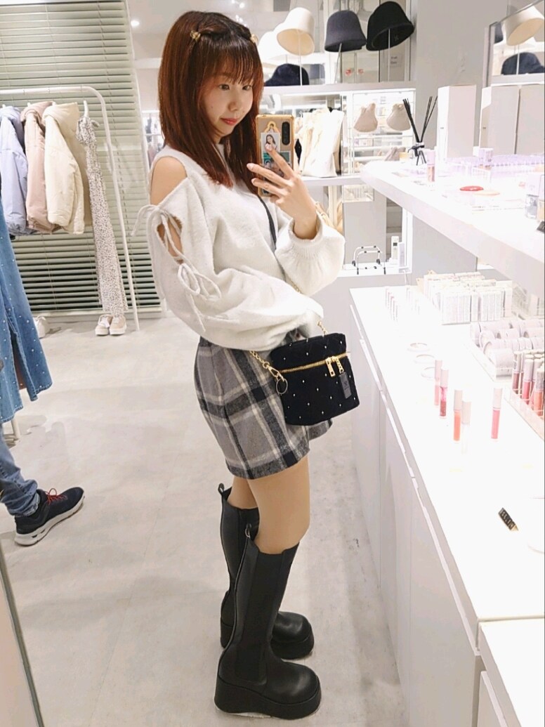 グレー系のニット/セーター、グレー系のスカート、ブラック系のショルダーバッグを着用したレディースの冬コーディネートの3枚目の写真