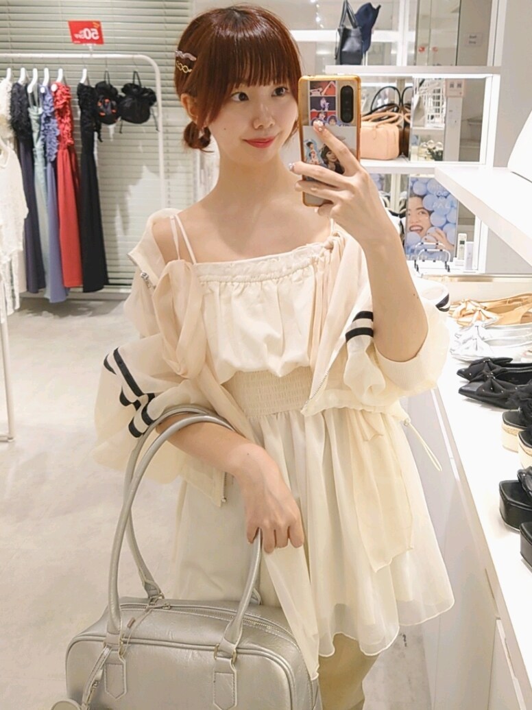 ホワイト系のキャミソール、ホワイト系のブルゾン、シルバー系のボストンバッグを着用したレディースの夏コーディネートの2枚目の写真