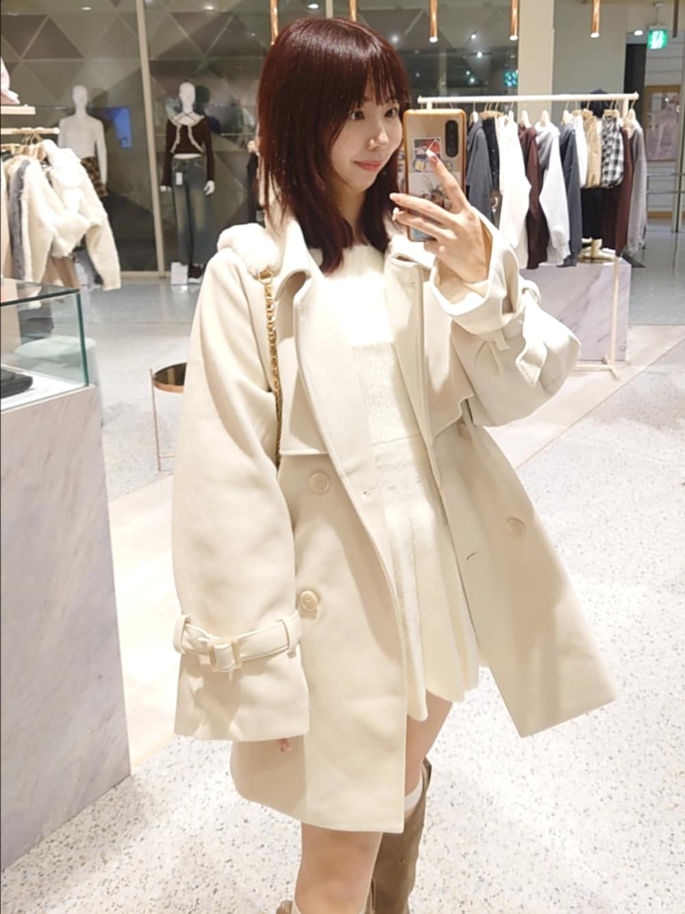 ホワイト系のチェスターコート、ホワイト系のワンピース、ベージュ系のショルダーバッグを着用したレディースの秋コーディネートの2枚目の写真