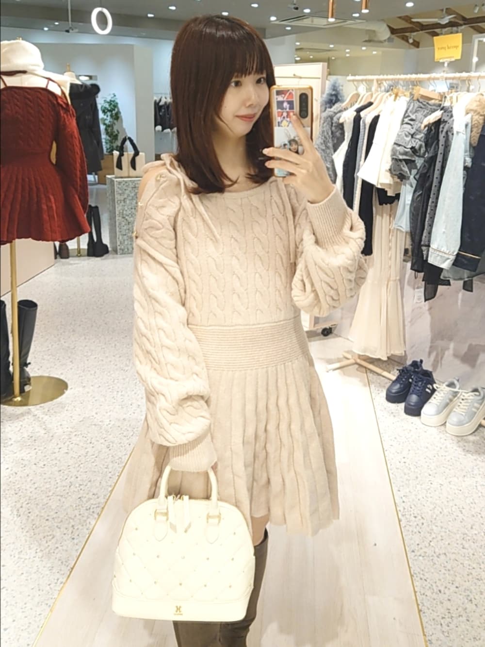 ホワイト系のブルゾン、ピンク系のワンピース、ホワイト系のハンドバッグを着用したレディースの冬コーディネートの2枚目の写真