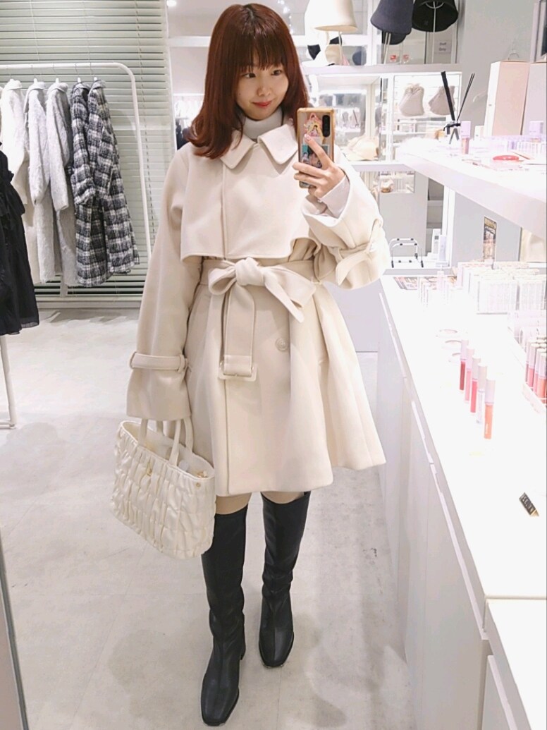 ホワイト系のピーコート、ブラック系のブーツ、ホワイト系のニット/セーターを着用したレディースの冬コーディネートの3枚目の写真