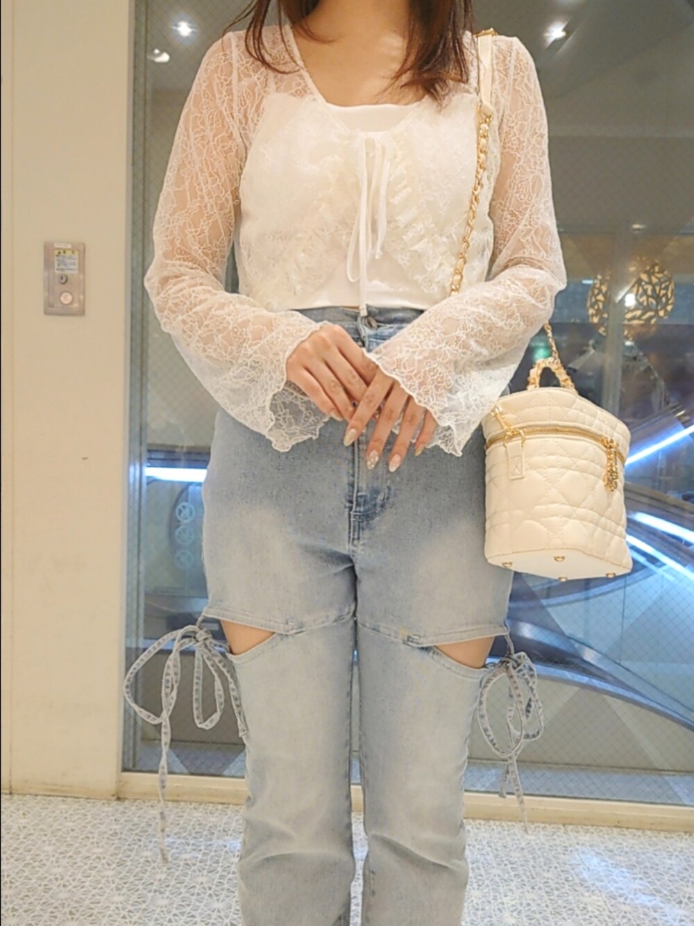 ホワイト系のカーディガン/ボレロ、ホワイト系のキャミソール、ブルー系のデニムパンツを着用したレディースの夏コーディネートの2枚目の写真