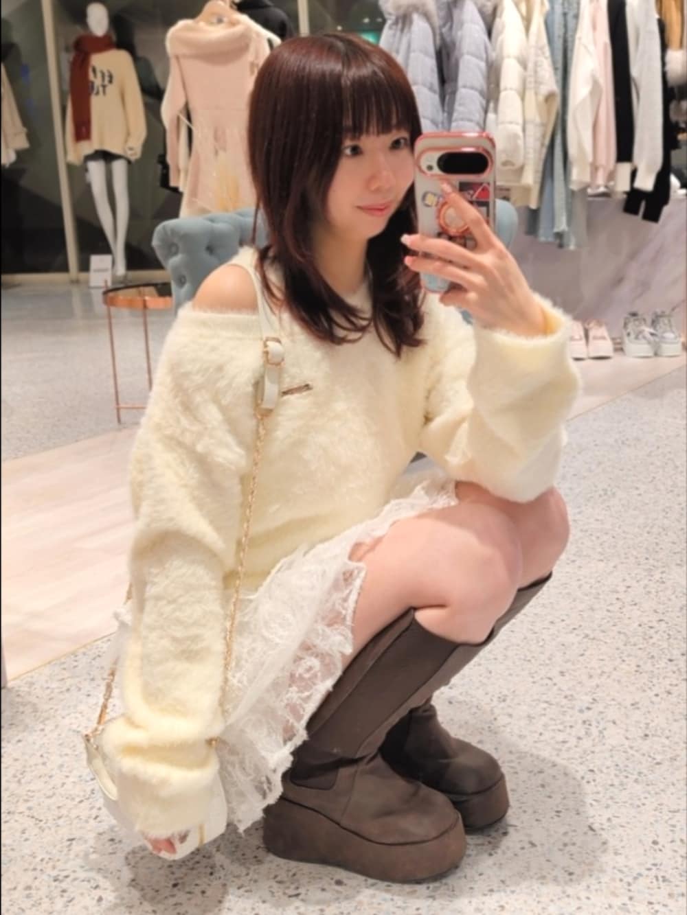 イエロー系のニット/セーター、ホワイト系のショルダーバッグ、ホワイト系のスカートを着用したレディースの冬コーディネートの4枚目の写真