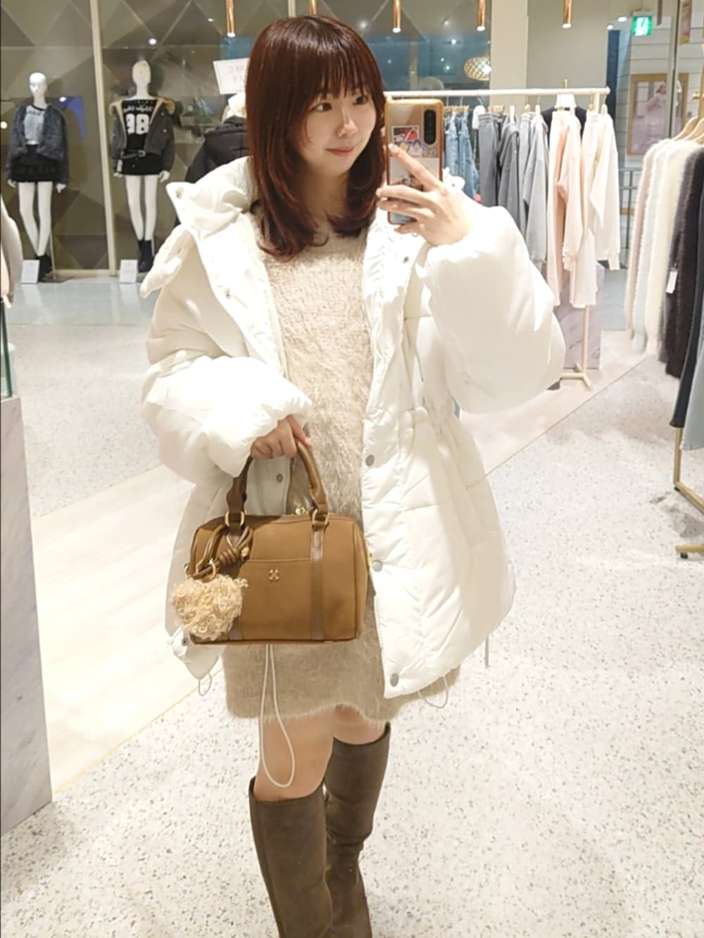 ホワイト系のダウンジャケット/コート、ピンク系のワンピース、イエロー系のボストンバッグを着用したレディースの冬コーディネートの2枚目の写真