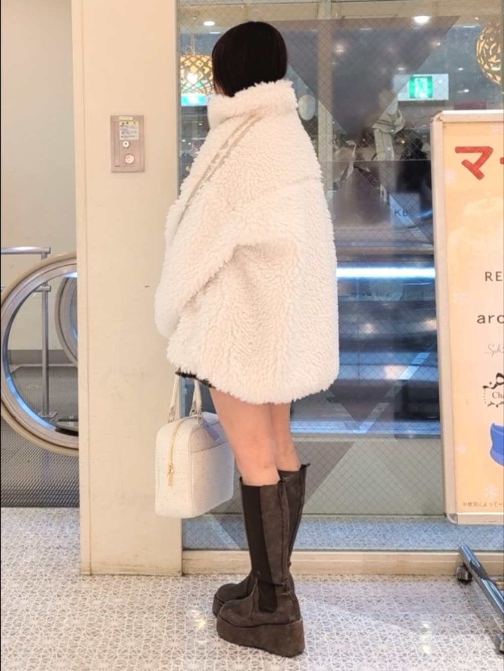 ホワイト系のブルゾン、ホワイト系のTシャツ/カットソー、ブラウン系のスカートを着用したレディースの冬コーディネートの4枚目の写真