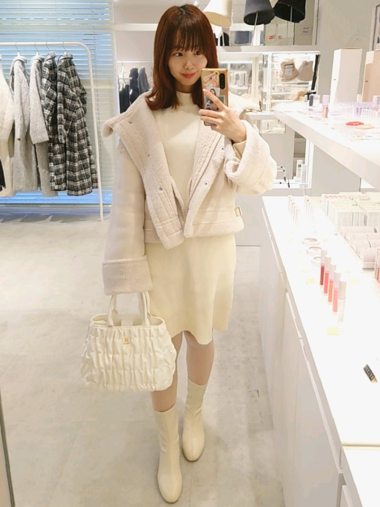 ホワイト系のブーツ、ホワイト系のハンドバッグ、ホワイト系のムートンコートを着用したレディースの冬コーディネートの4枚目の写真