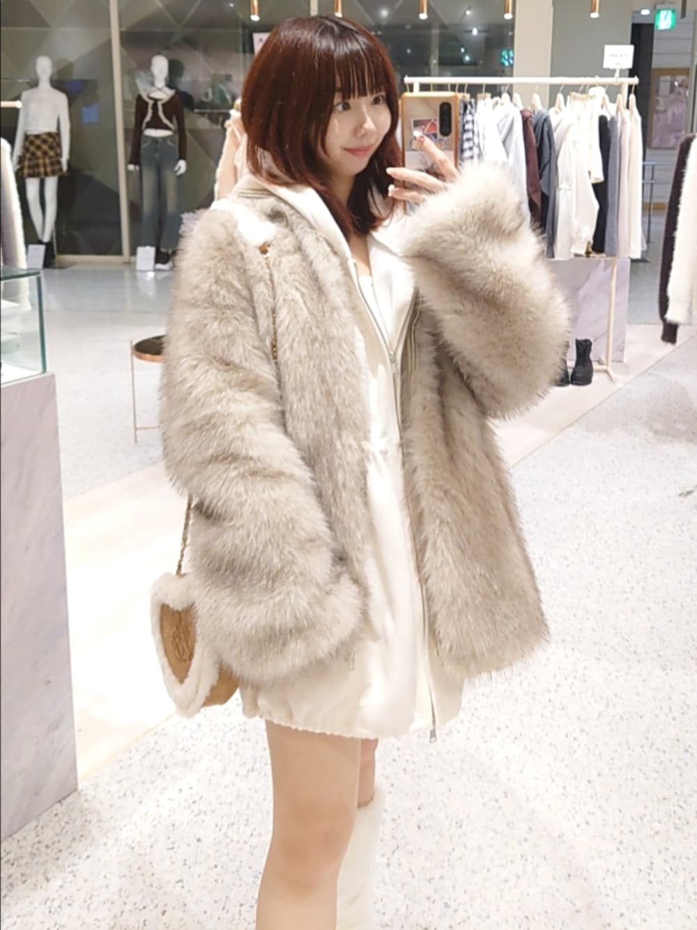 ベージュ系のその他アウター、ホワイト系のパーカー、ベージュ系のショルダーバッグを着用したレディースの秋コーディネートの2枚目の写真