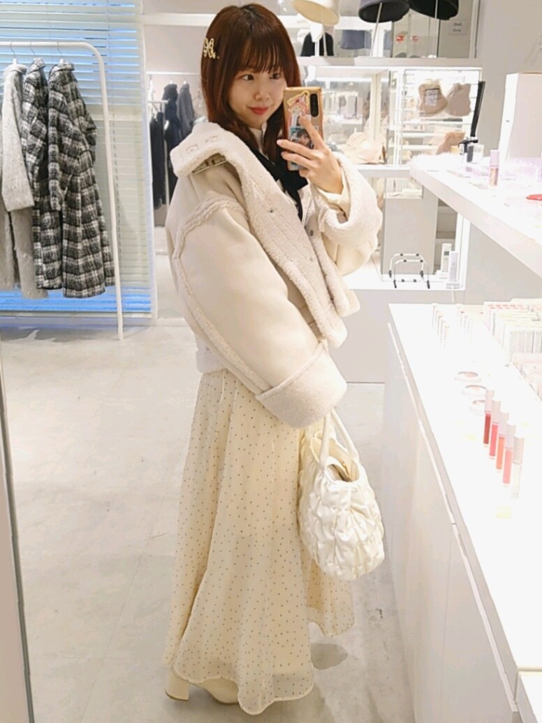 ホワイト系のブーツ、ホワイト系のハンドバッグ、ホワイト系のムートンコートを着用したレディースの冬コーディネートの3枚目の写真