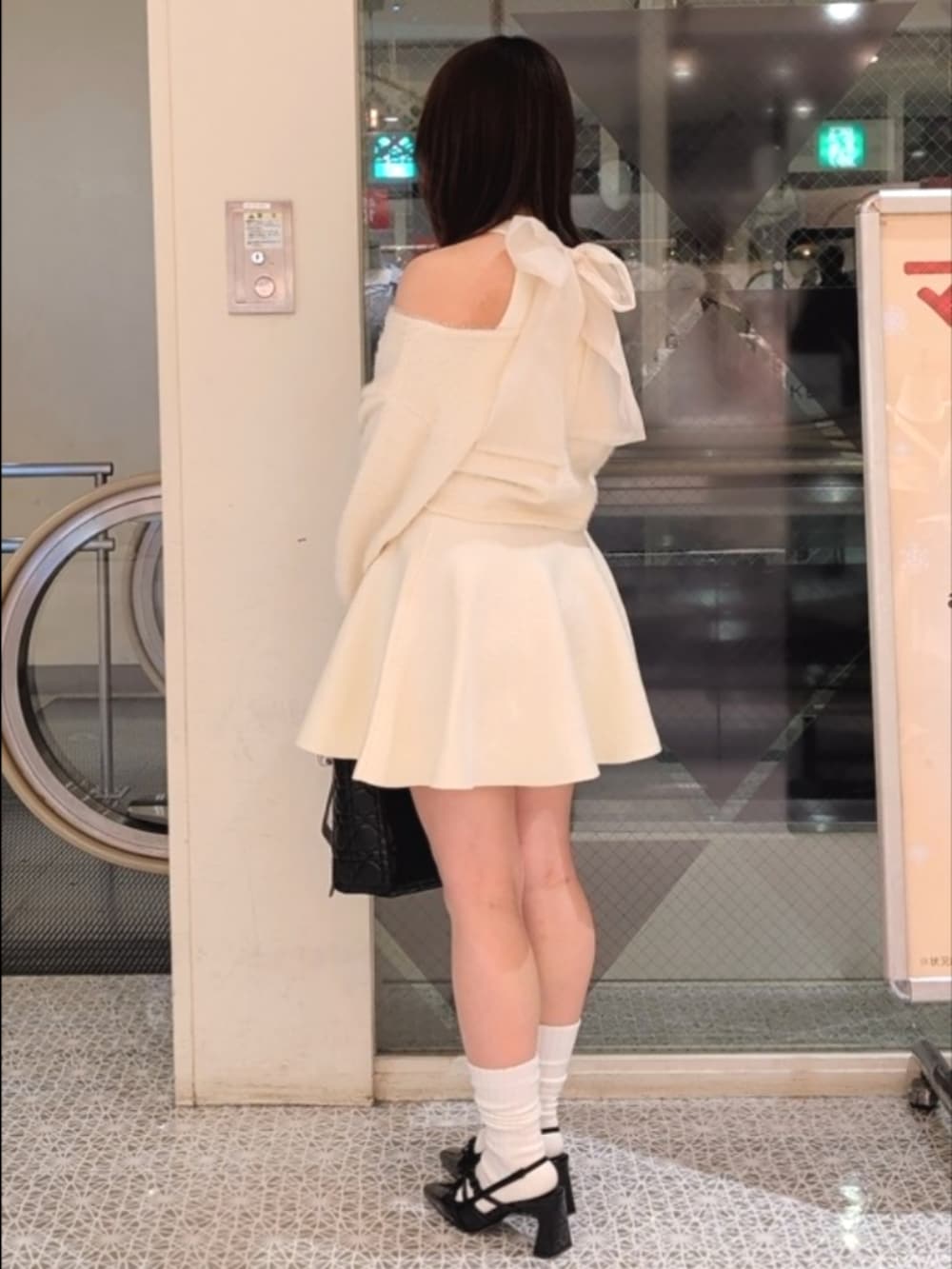 ホワイト系のワンピース、ブラック系のトートバッグ、ブラック系のパンプスを着用したレディースの冬コーディネートの4枚目の写真