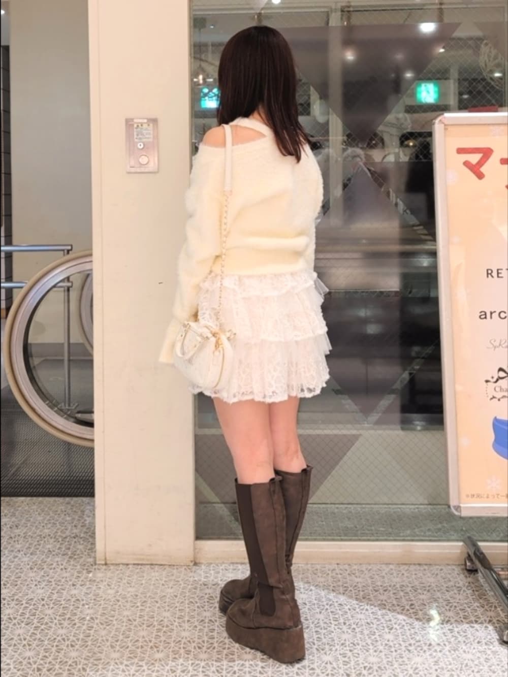 イエロー系のニット/セーター、ホワイト系のショルダーバッグ、ホワイト系のスカートを着用したレディースの冬コーディネートの3枚目の写真