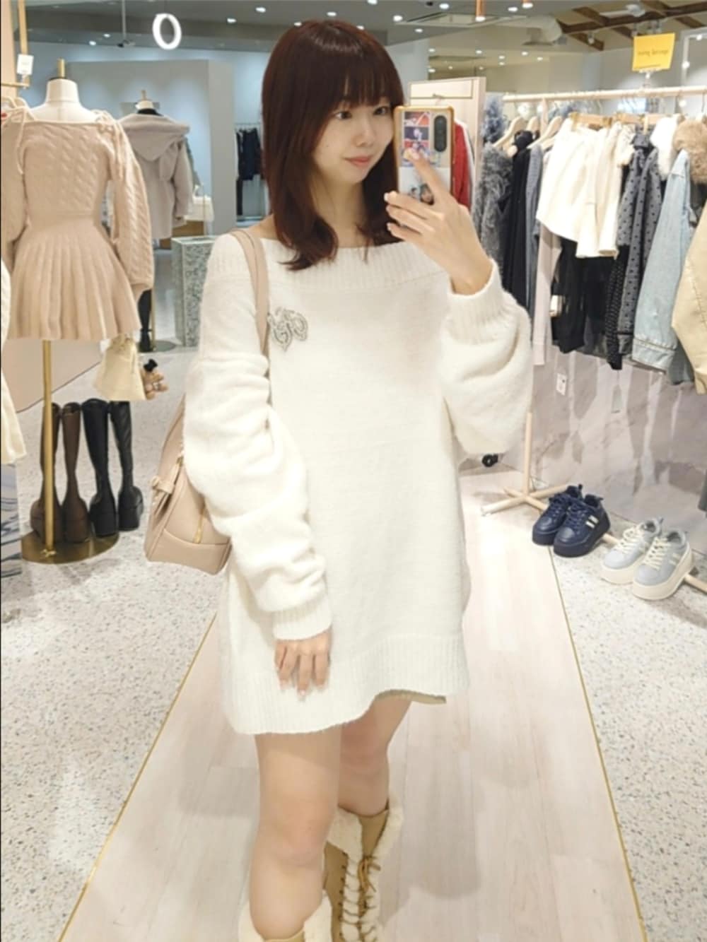 ホワイト系のニット/セーター、ピンク系のボストンバッグ、ベージュ系のブーツを着用したレディースの冬コーディネートの2枚目の写真