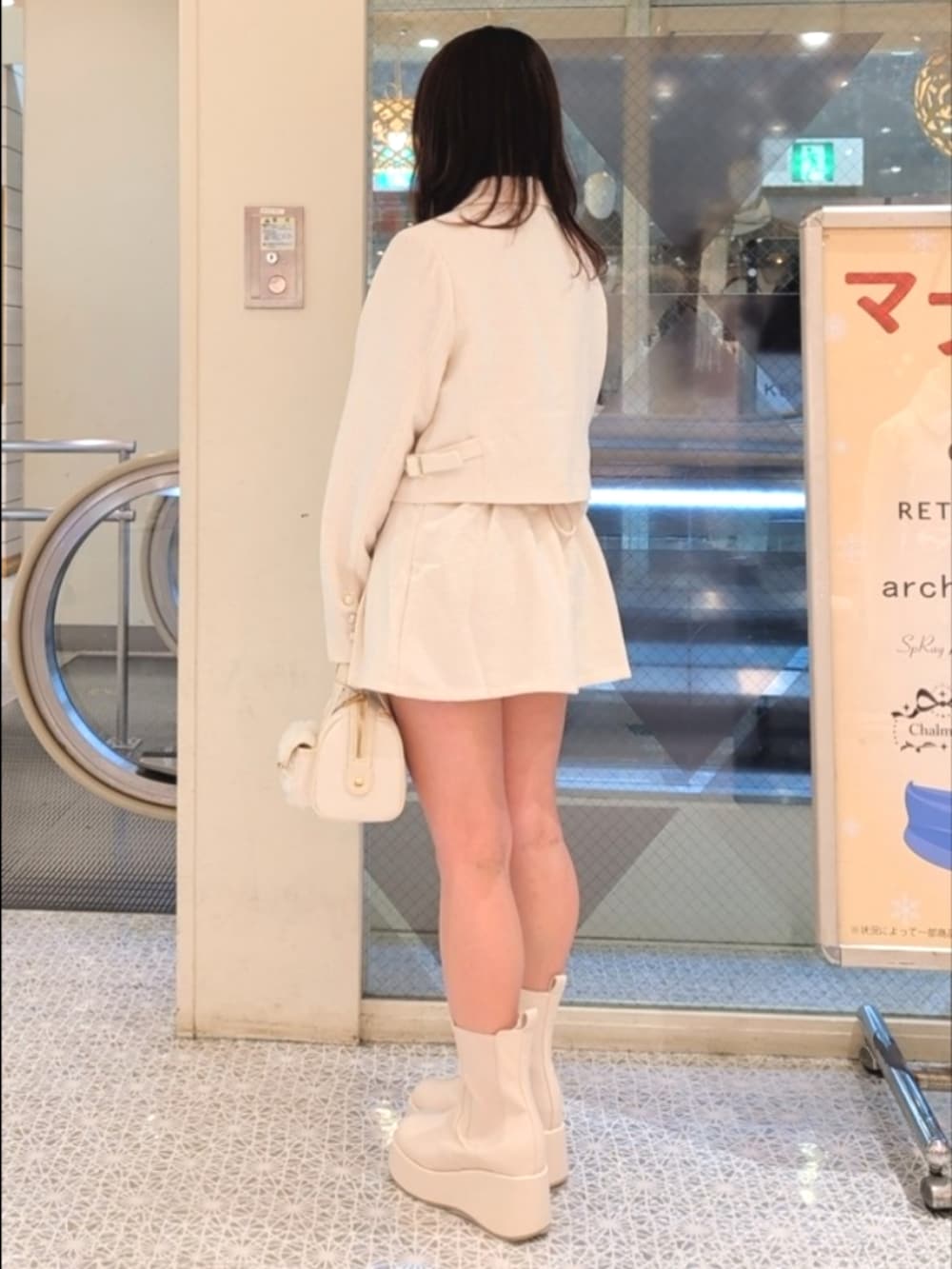 ホワイト系のテーラードジャケット、ホワイト系のスカート、ホワイト系のショルダーバッグを着用したレディースの冬コーディネートの3枚目の写真