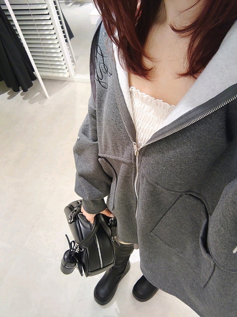 グレー系のパーカー、ホワイト系のキャミソール、グレー系のスカートを着用したレディースの冬コーディネートの3枚目の写真