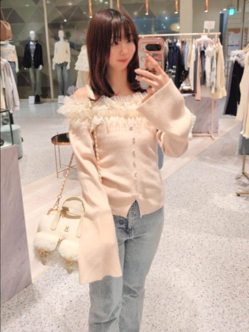 ピンク系のニット/セーター、ブルー系のデニムパンツ、ホワイト系のボストンバッグを着用したレディースの冬コーディネートの2枚目の写真