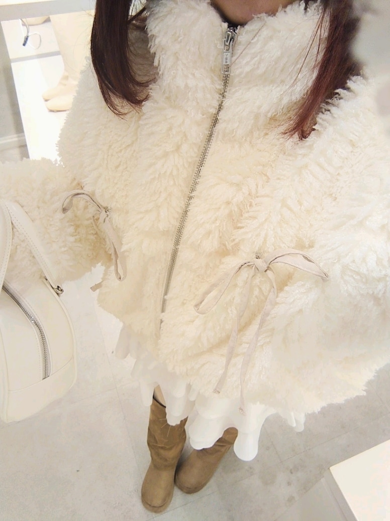 ホワイト系のブルゾン、ホワイト系のスカート、ホワイト系のハンドバッグを着用したレディースの冬コーディネートの3枚目の写真