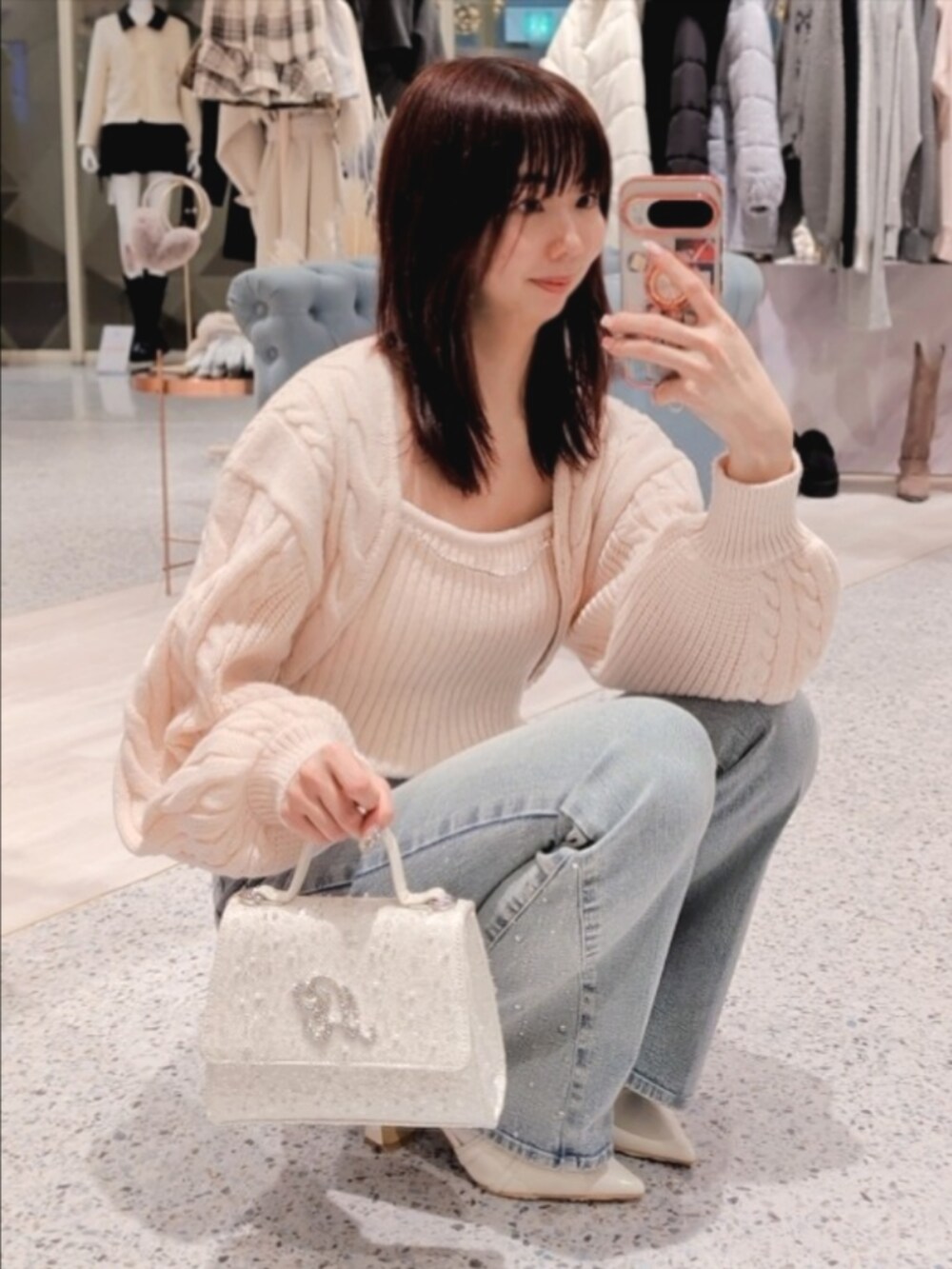 ピンク系のアンサンブル、ブルー系のデニムパンツ、ホワイト系のショルダーバッグを着用したレディースの冬コーディネートの2枚目の写真