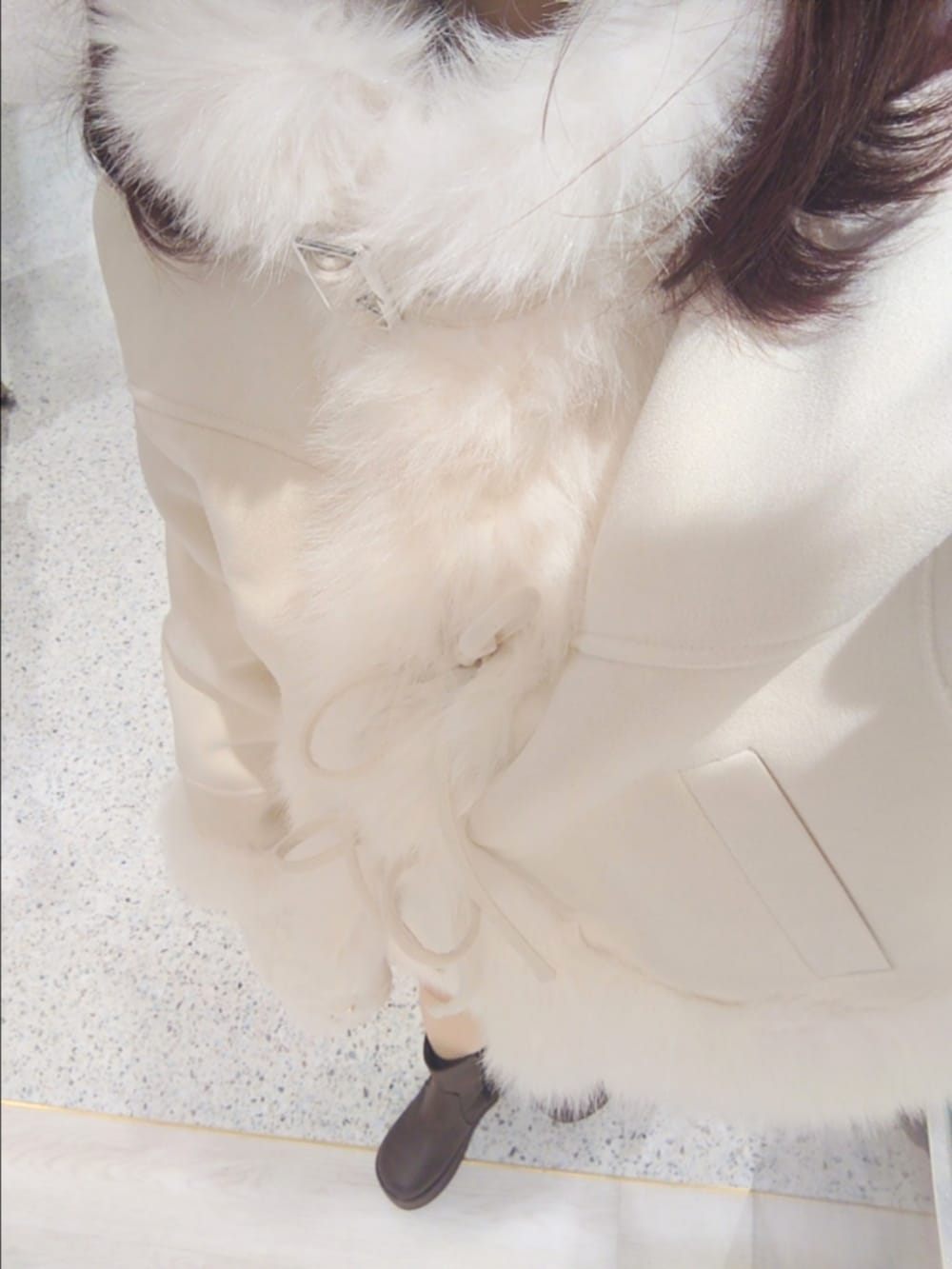 ホワイト系のムートンコート、ホワイト系のスカート、ホワイト系のショルダーバッグを着用したレディースの秋コーディネートの2枚目の写真