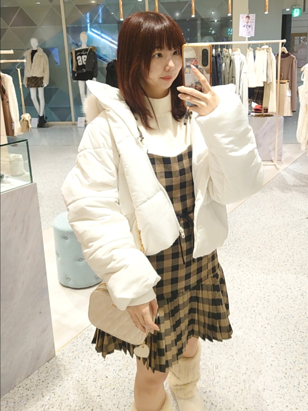 ホワイト系のダウンジャケット/コート、ホワイト系のニット/セーター、ベージュ系のワンピースを着用したレディースの秋コーディネートの2枚目の写真