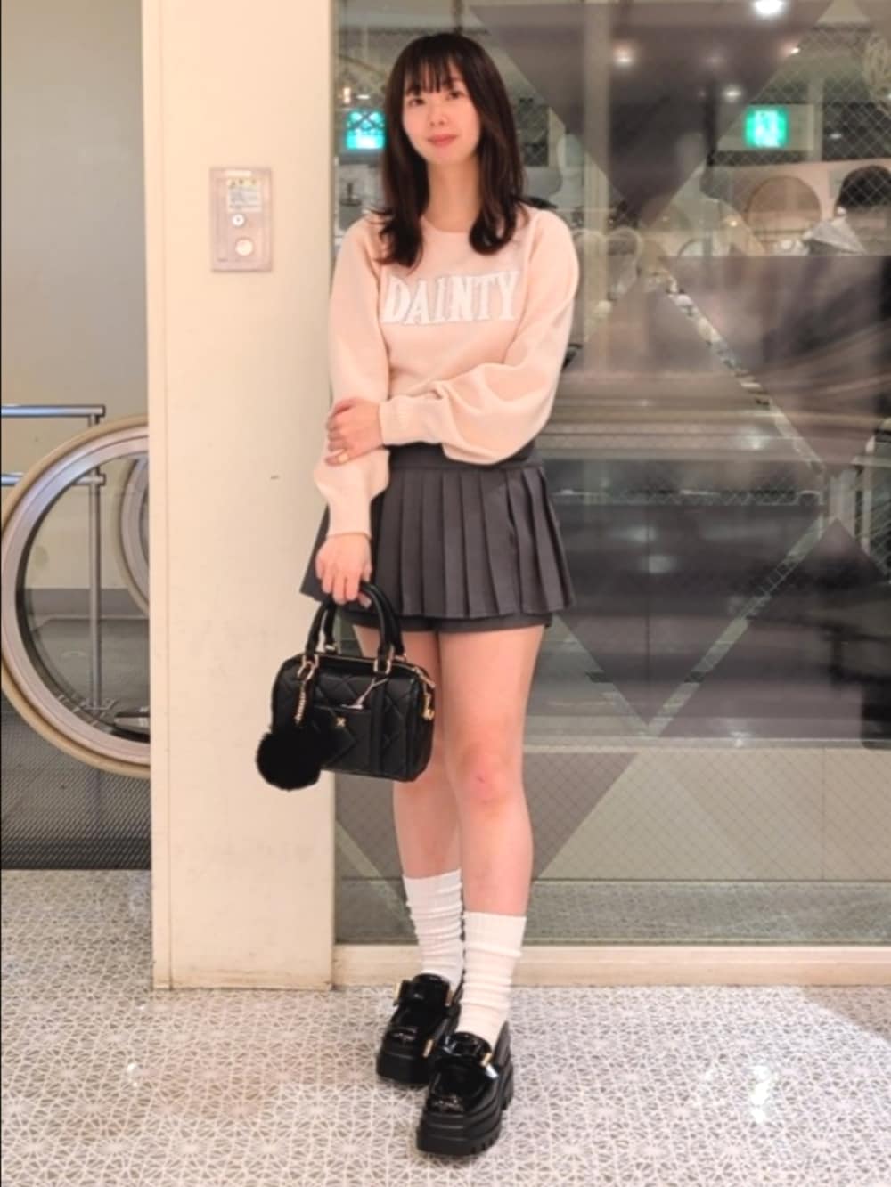 ピンク系のニット/セーター、グレー系のスカート、ブラック系のローファーを着用したレディースの冬コーディネートの3枚目の写真