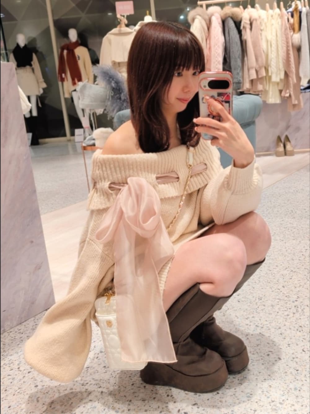 ピンク系のワンピース、ホワイト系のショルダーバッグ、ブラウン系のブーツを着用したレディースの冬コーディネートの3枚目の写真