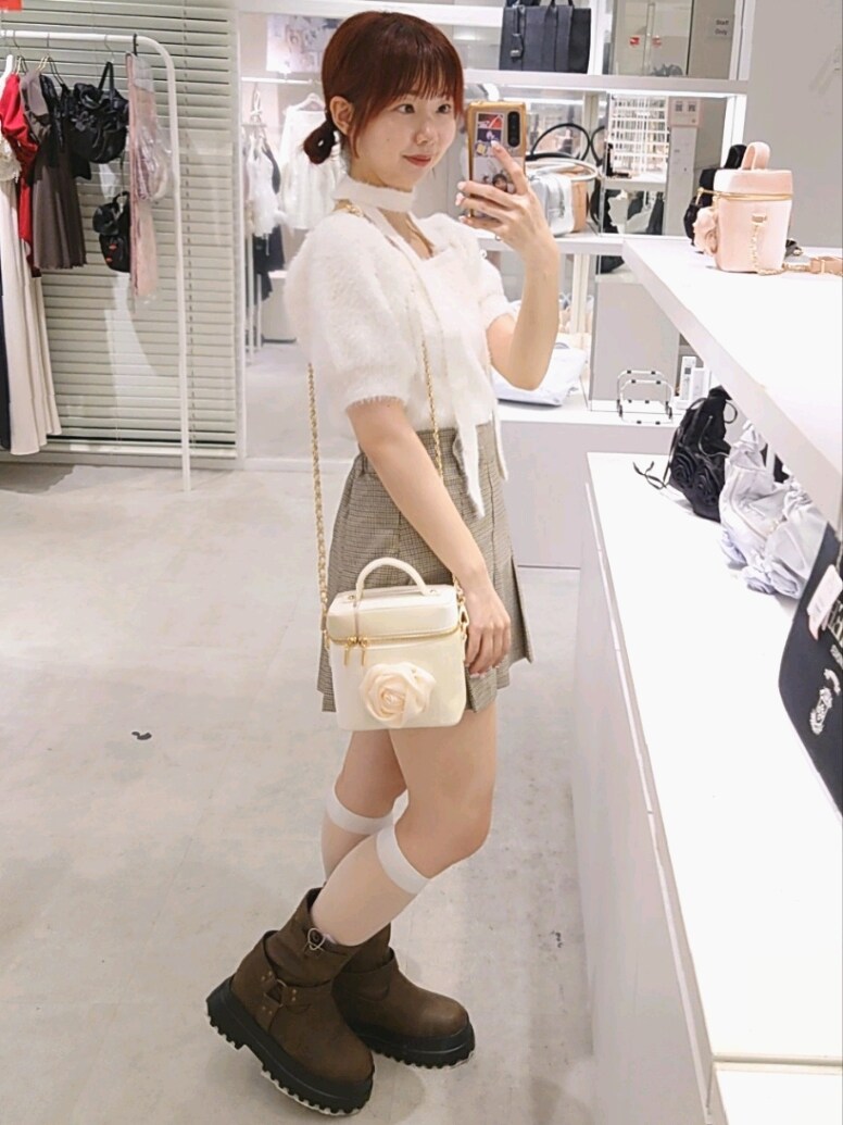 ホワイト系のニット/セーター、ベージュ系のスカート、ブラウン系のブーツを着用したレディースの夏コーディネートの3枚目の写真