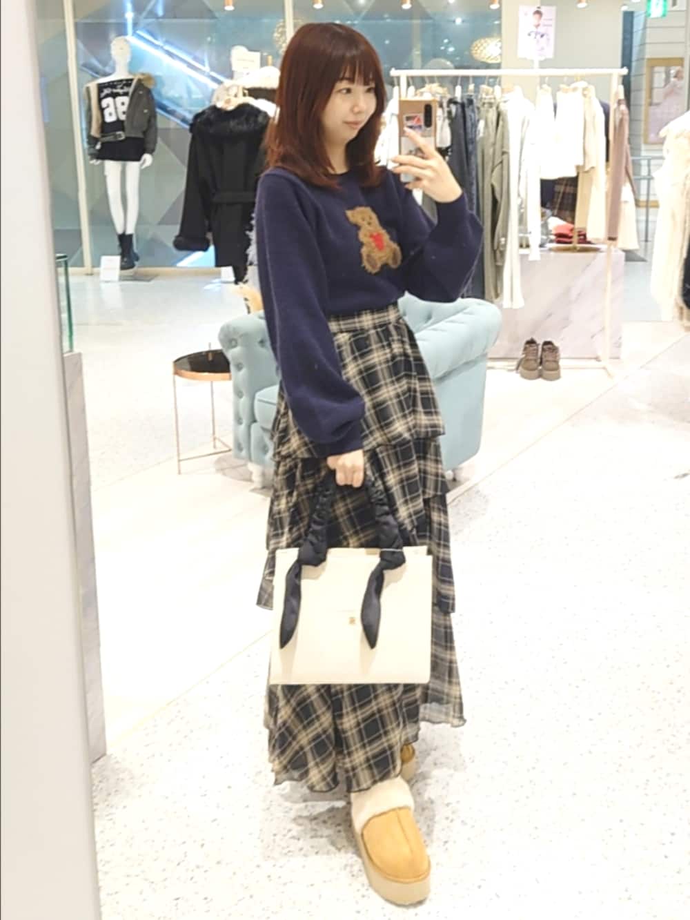 ホワイト系のダウンジャケット/コート、ブルー系のニット/セーター、ブラック系のスカートを着用したレディースの秋コーディネートの4枚目の写真