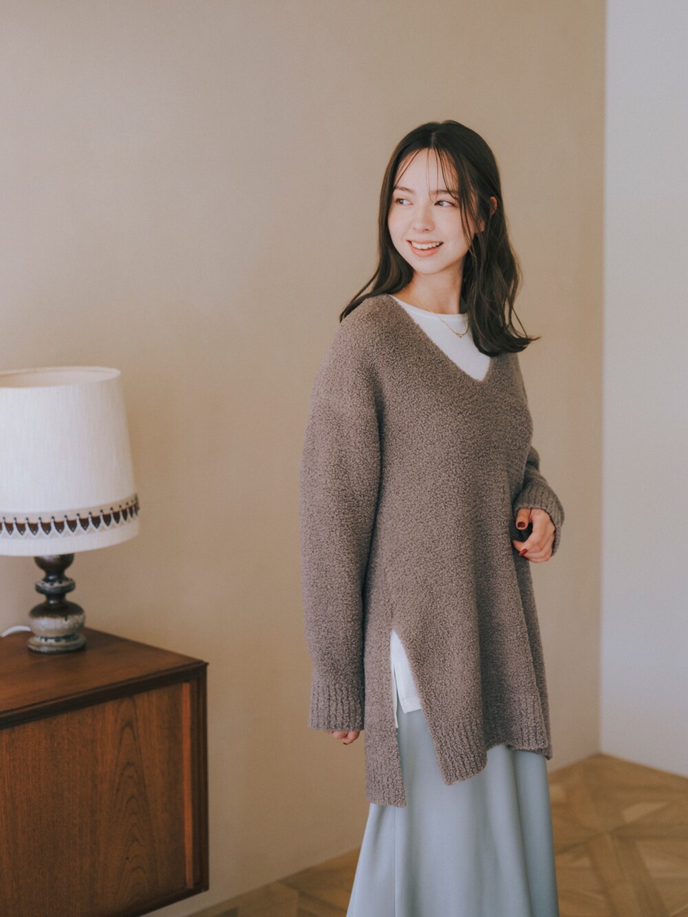 ブラウン系のニット/セーター、ホワイト系のTシャツ/カットソー、ブルー系のスカートを着用したレディースの秋コーディネートの2枚目の写真