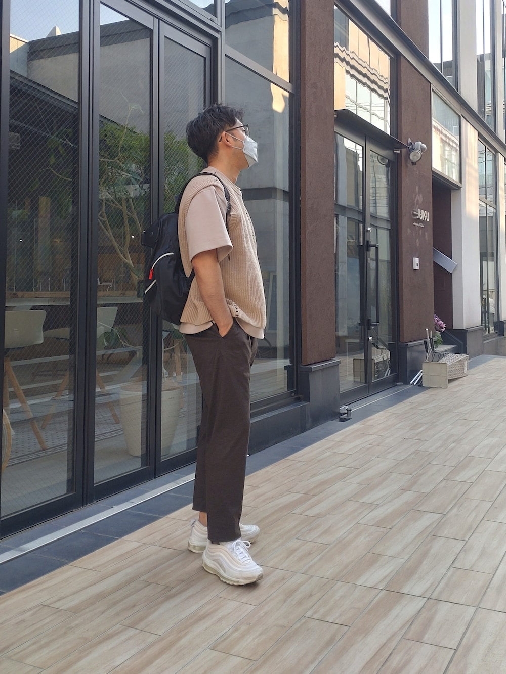 ベージュ系のベスト、ベージュ系のTシャツ/カットソー、ブラウン系のスラックスを着用したメンズの春コーディネートの2枚目の写真