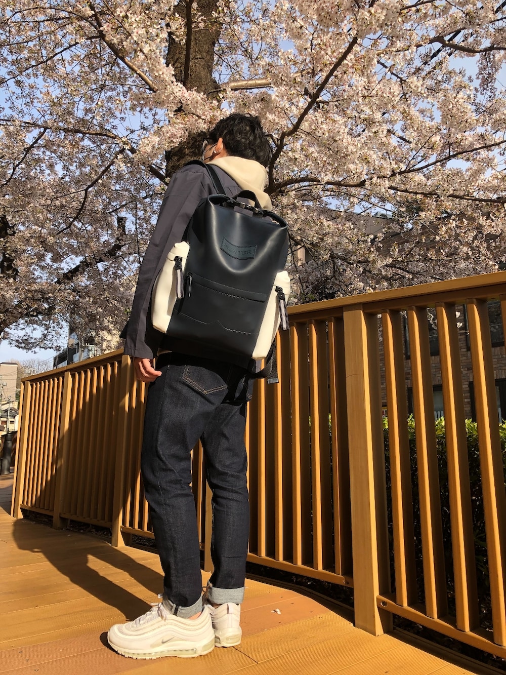 ベージュ系のパーカー、ホワイト系のスニーカー、ブルー系のデニムパンツを着用したメンズの春コーディネートの3枚目の写真
