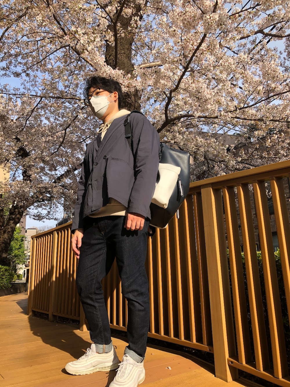 ベージュ系のパーカー、ホワイト系のスニーカー、ブルー系のデニムパンツを着用したメンズの春コーディネートの2枚目の写真