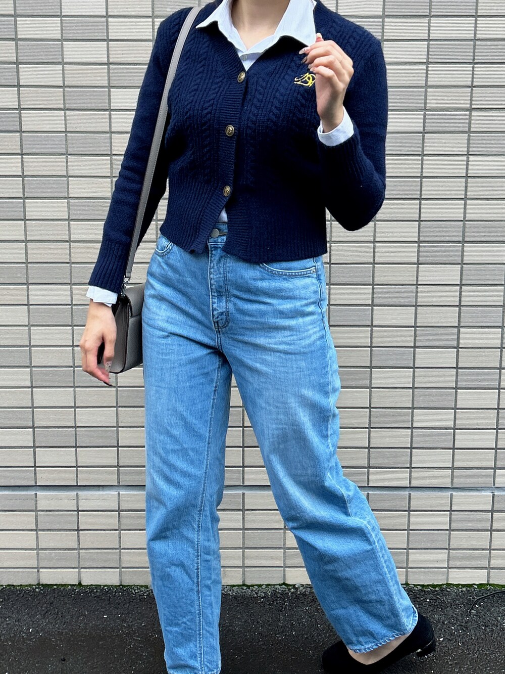 グレー系のショルダーバッグ、ブラック系のパンプス、ブルー系のデニムパンツを着用したレディースの秋コーディネートの4枚目の写真