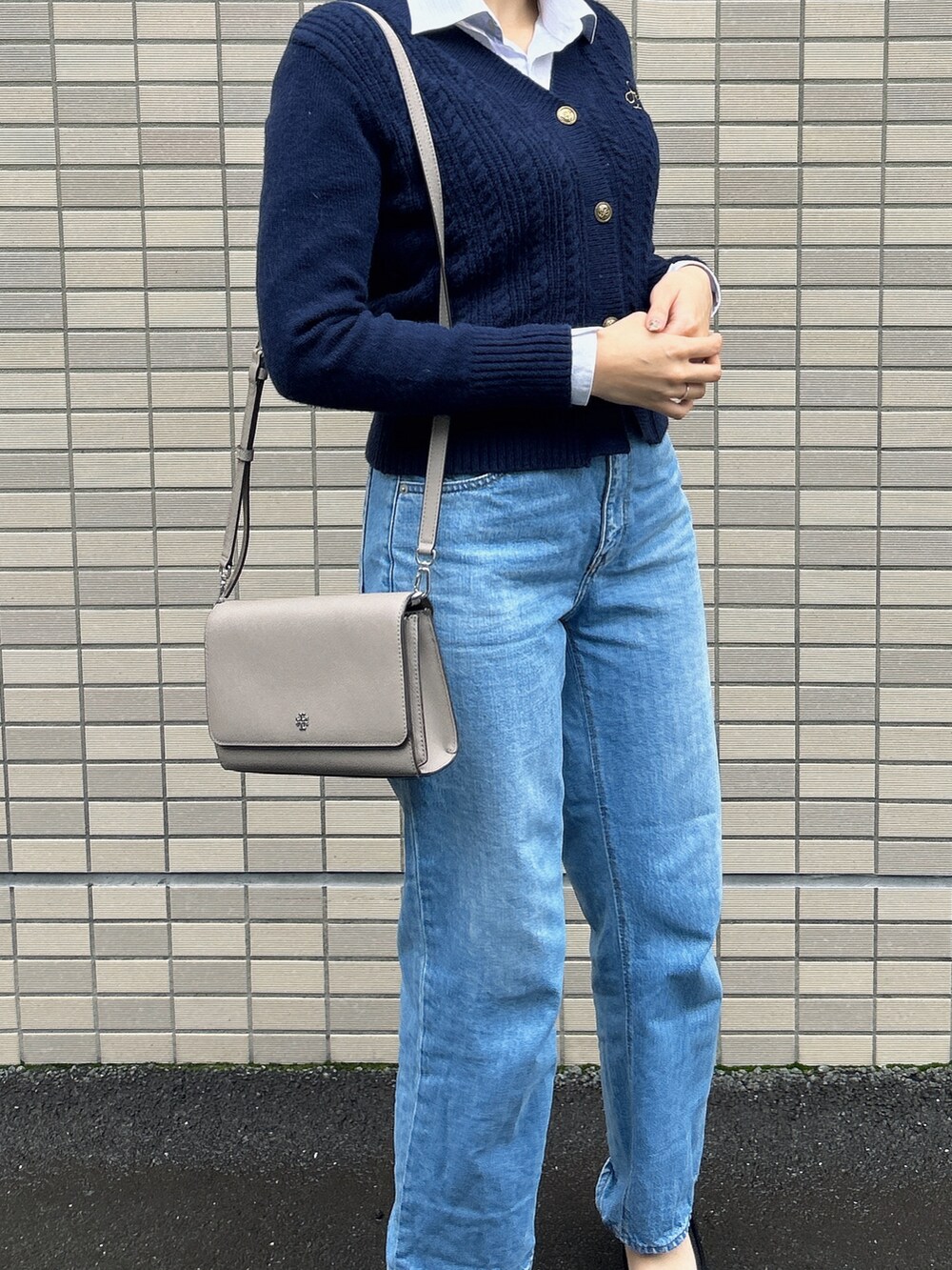 グレー系のショルダーバッグ、ブラック系のパンプス、ブルー系のデニムパンツを着用したレディースの秋コーディネートの2枚目の写真