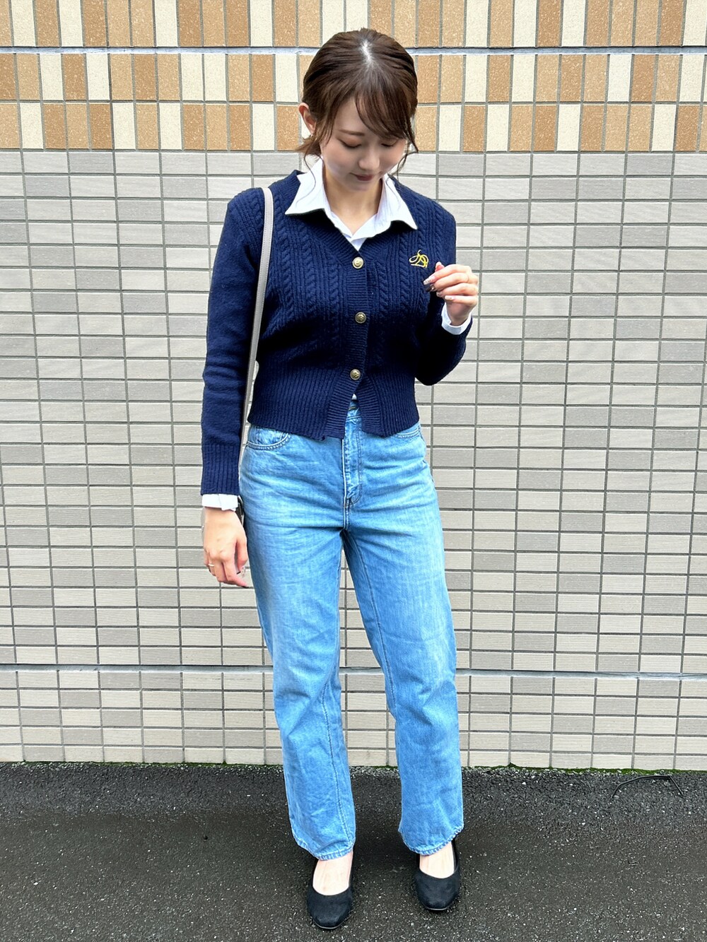 グレー系のショルダーバッグ、ブラック系のパンプス、ブルー系のデニムパンツを着用したレディースの秋コーディネートの5枚目の写真