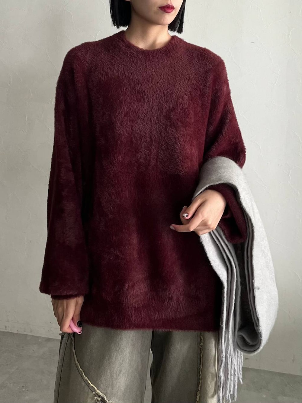 レッド系のニット/セーター、ブラック系のスニーカー、ベージュ系のデニムパンツを着用したレディースの秋コーディネートの2枚目の写真