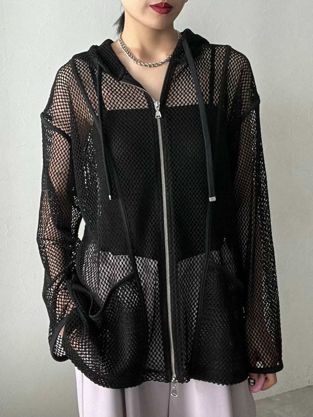 ブラック系のサンダル、ブラック系のパーカー、ピンク系のスラックスを着用したレディースの春コーディネートの2枚目の写真