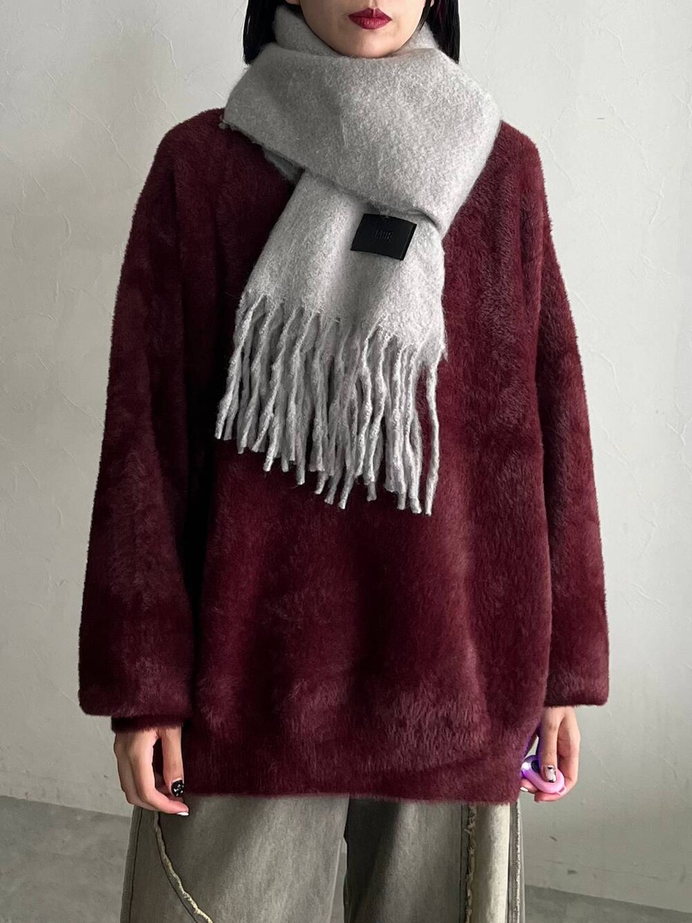 レッド系のニット/セーター、ブラック系のスニーカー、ベージュ系のデニムパンツを着用したレディースの秋コーディネートの3枚目の写真