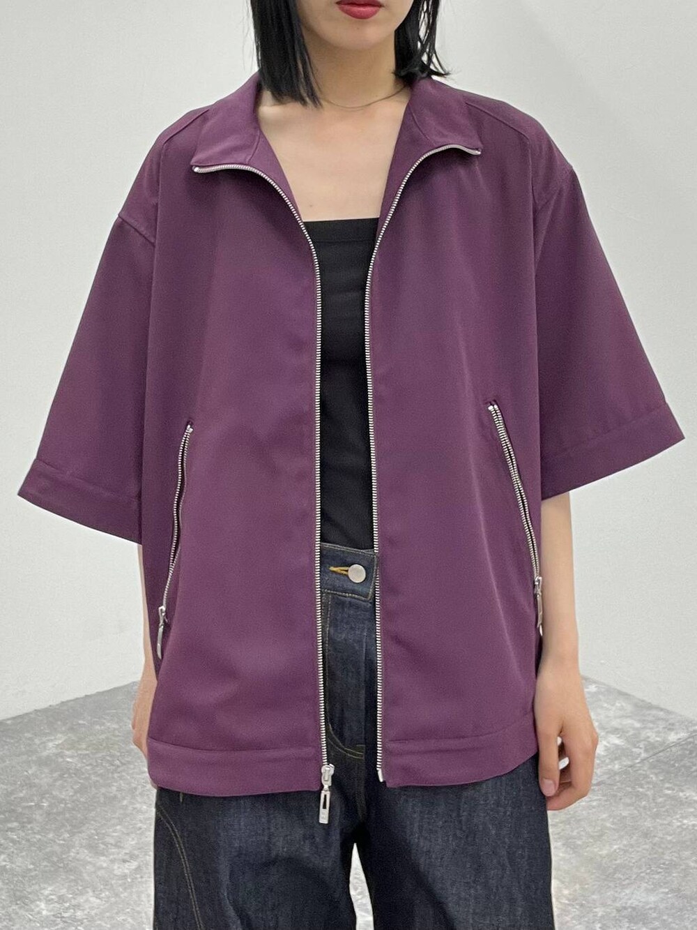 ブルー系のデニムパンツ、パープル系のブルゾン、ブラック系のドレスシューズを着用したレディースの春コーディネートの2枚目の写真
