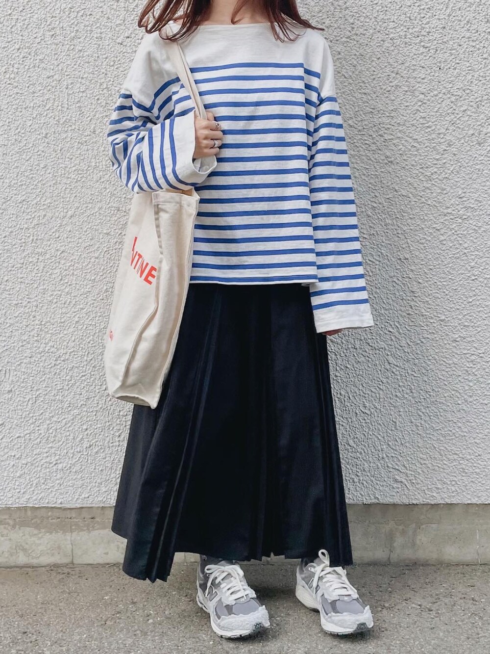 ホワイト系のTシャツ/カットソー、ブラック系のスカート、グレー系のスニーカーを着用したレディースの春コーディネートの2枚目の写真