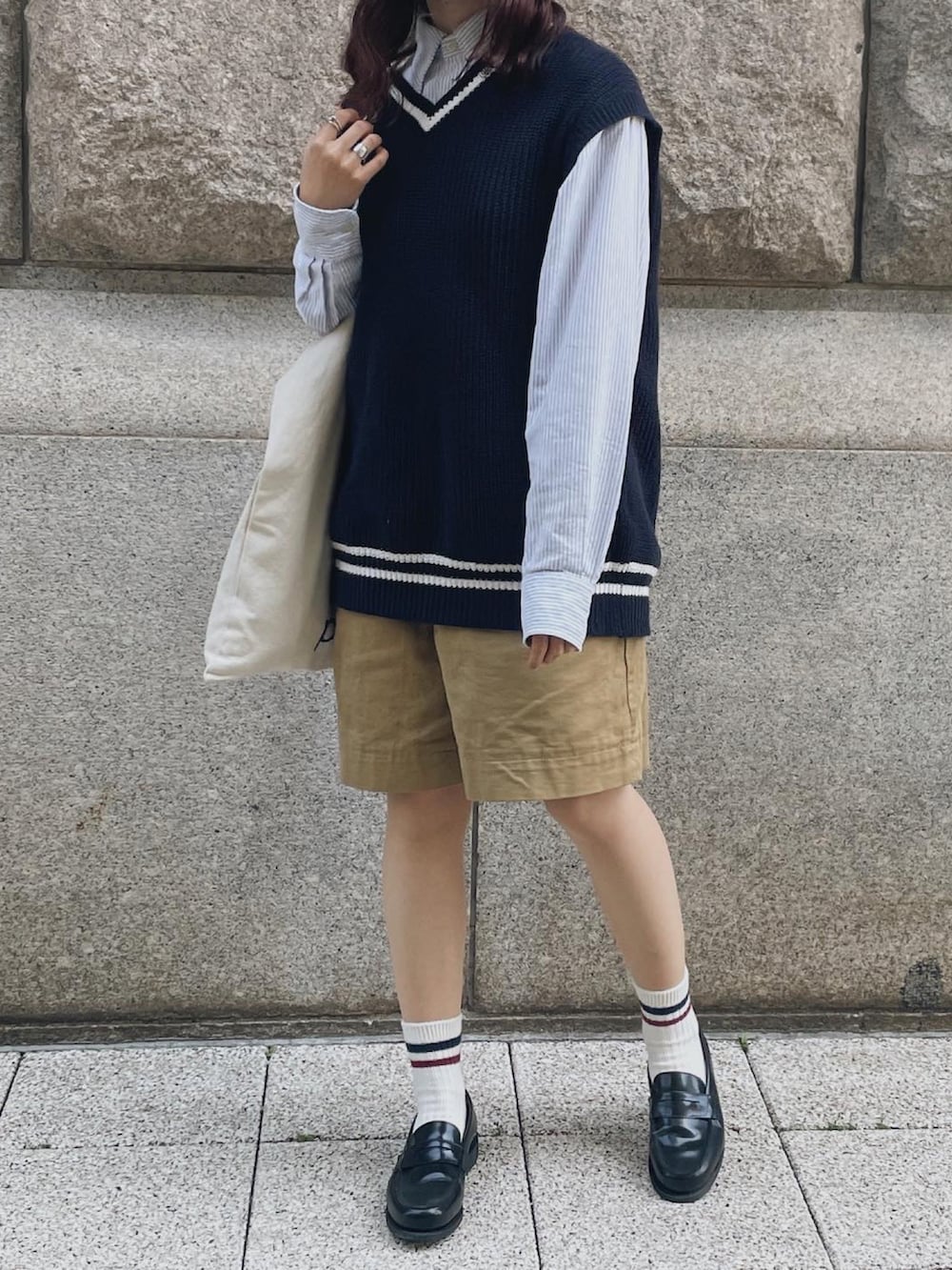 ブラック系のベスト、ブルー系のシャツ/ブラウス、ベージュ系のトートバッグを着用したレディースの春コーディネートの2枚目の写真