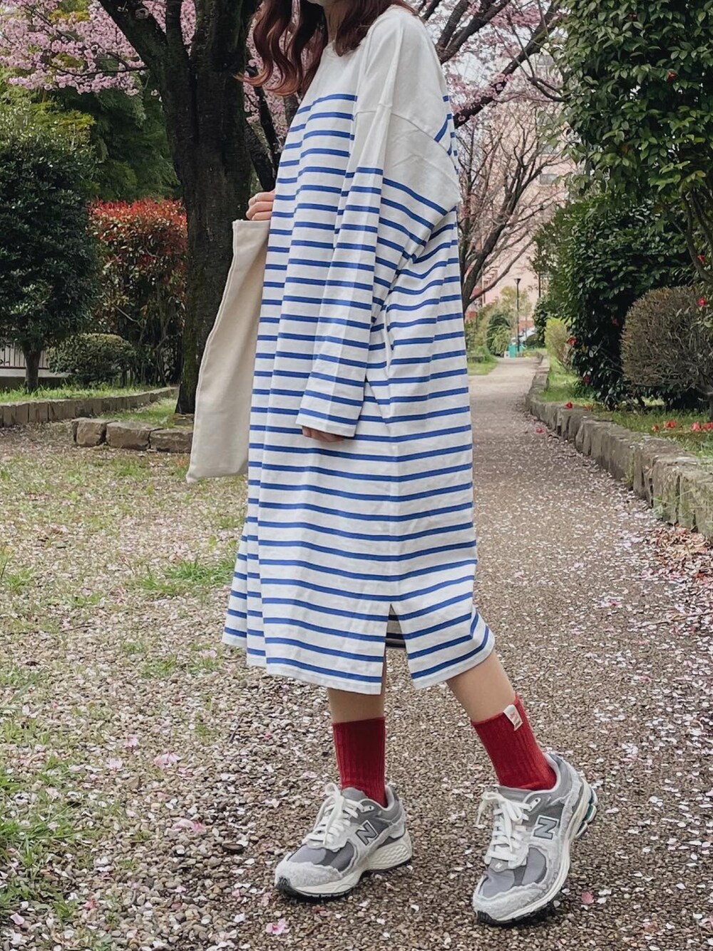 ホワイト系のワンピース、グレー系のスニーカー、ベージュ系のトートバッグを着用したレディースの春コーディネートの2枚目の写真