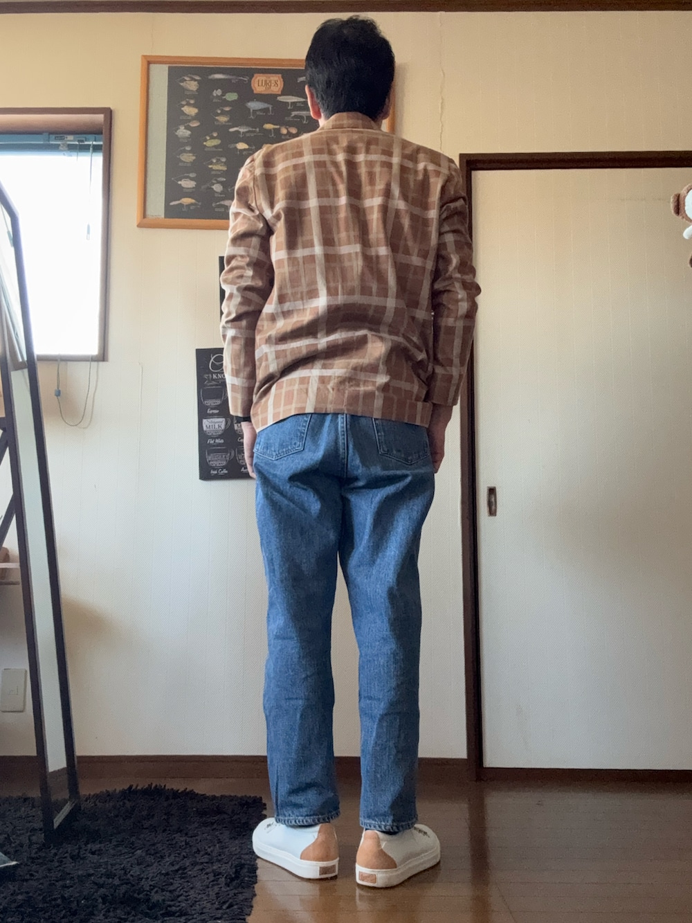 ブルー系のデニムパンツ、ブラウン系のテーラードジャケット、ホワイト系のスニーカーを着用したメンズの春コーディネートの2枚目の写真