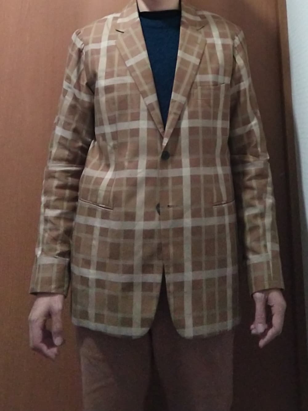 ブルー系のトレンチコート、ブラウン系のテーラードジャケット、ブラウン系のチノパンツを着用したメンズの冬コーディネートの2枚目の写真