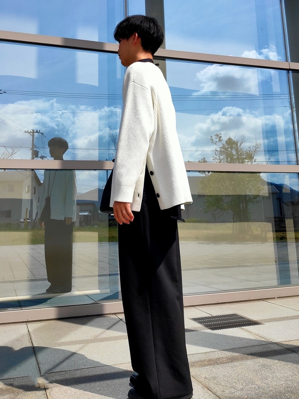 ブラック系のスラックス、ブラック系のスニーカー、ブラック系のショルダーバッグを着用したメンズの春コーディネートの2枚目の写真