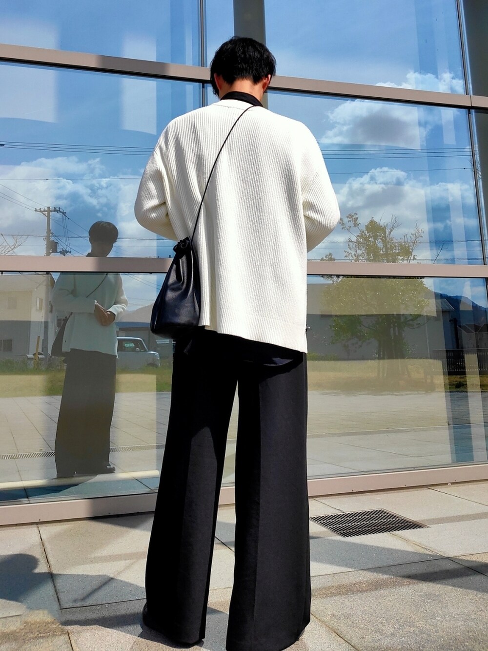 ブラック系のスラックス、ブラック系のスニーカー、ブラック系のショルダーバッグを着用したメンズの春コーディネートの3枚目の写真