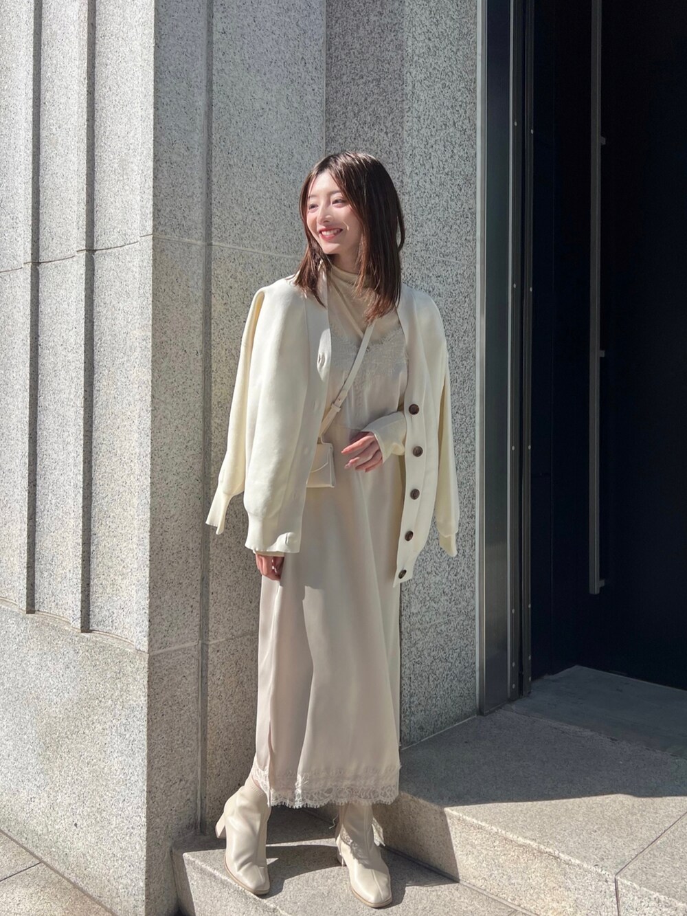 ベージュ系のワンピース、ホワイト系のカーディガン/ボレロ、ベージュ系のTシャツ/カットソーを着用したレディースの春コーディネートの2枚目の写真