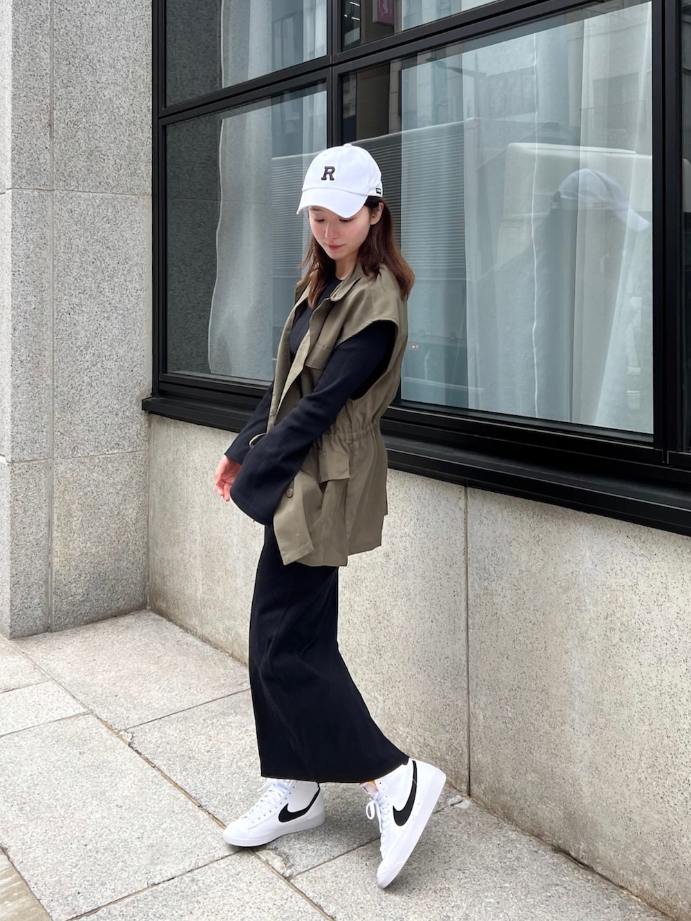 ブラック系のワンピース、グリーン系のベスト、ホワイト系のスニーカーを着用したレディースの春コーディネートの2枚目の写真