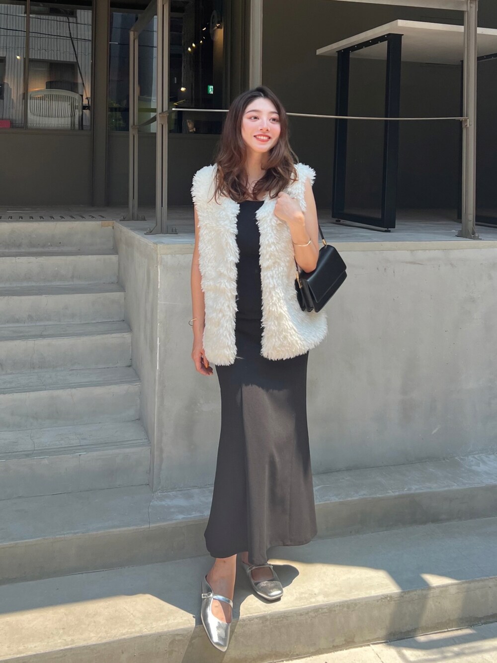 ブラック系のワンピース、ホワイト系のベスト、シルバー系のパンプスを着用したレディースの夏コーディネートの2枚目の写真