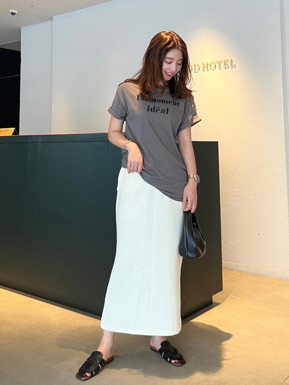 グレー系のTシャツ/カットソー、ホワイト系のスカート、ブラック系のサンダルを着用したレディースの夏コーディネートの2枚目の写真