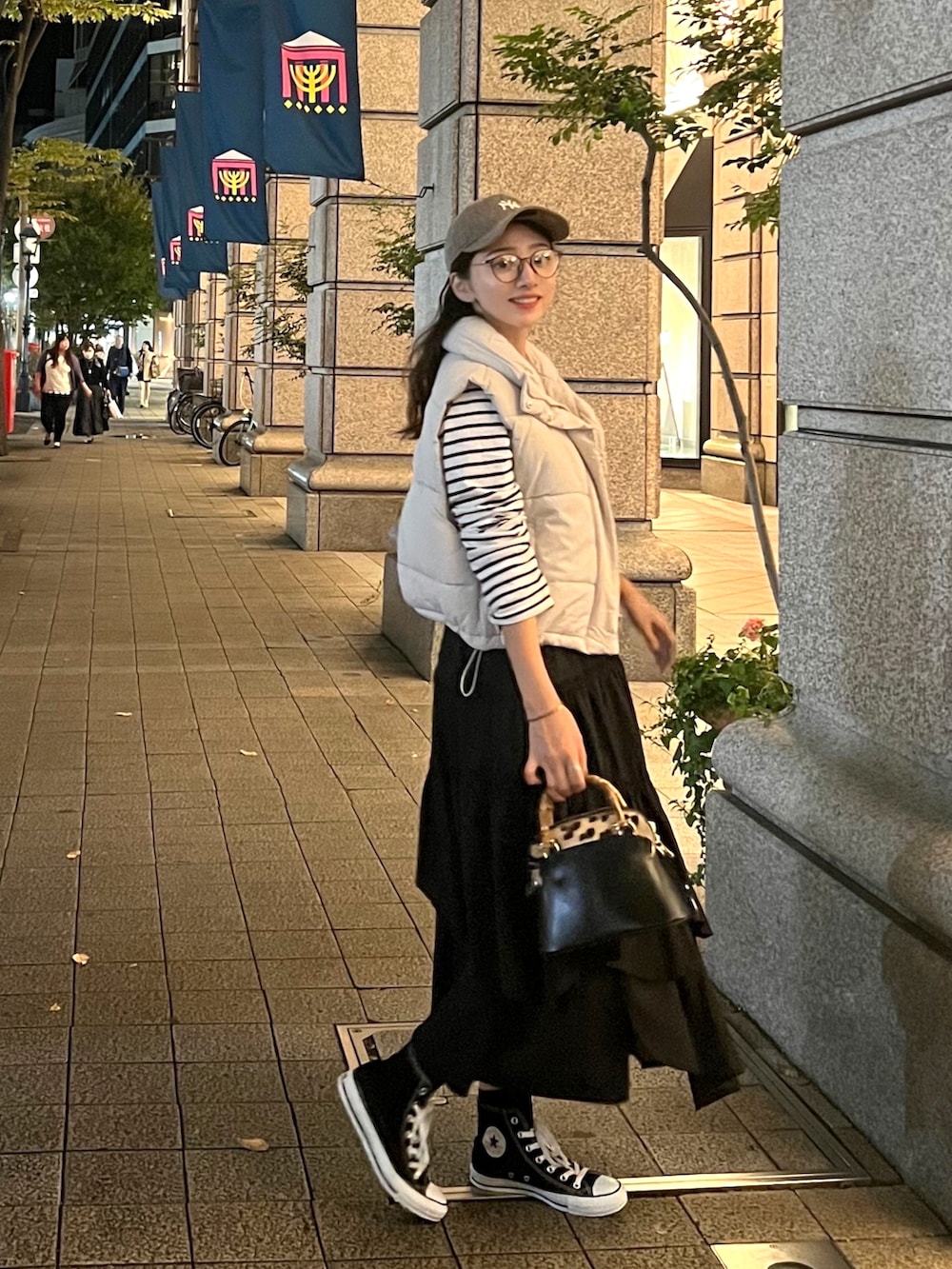 ホワイト系のダウンベスト、ホワイト系のTシャツ/カットソー、ブラック系のスカートを着用したレディースの秋コーディネートの2枚目の写真