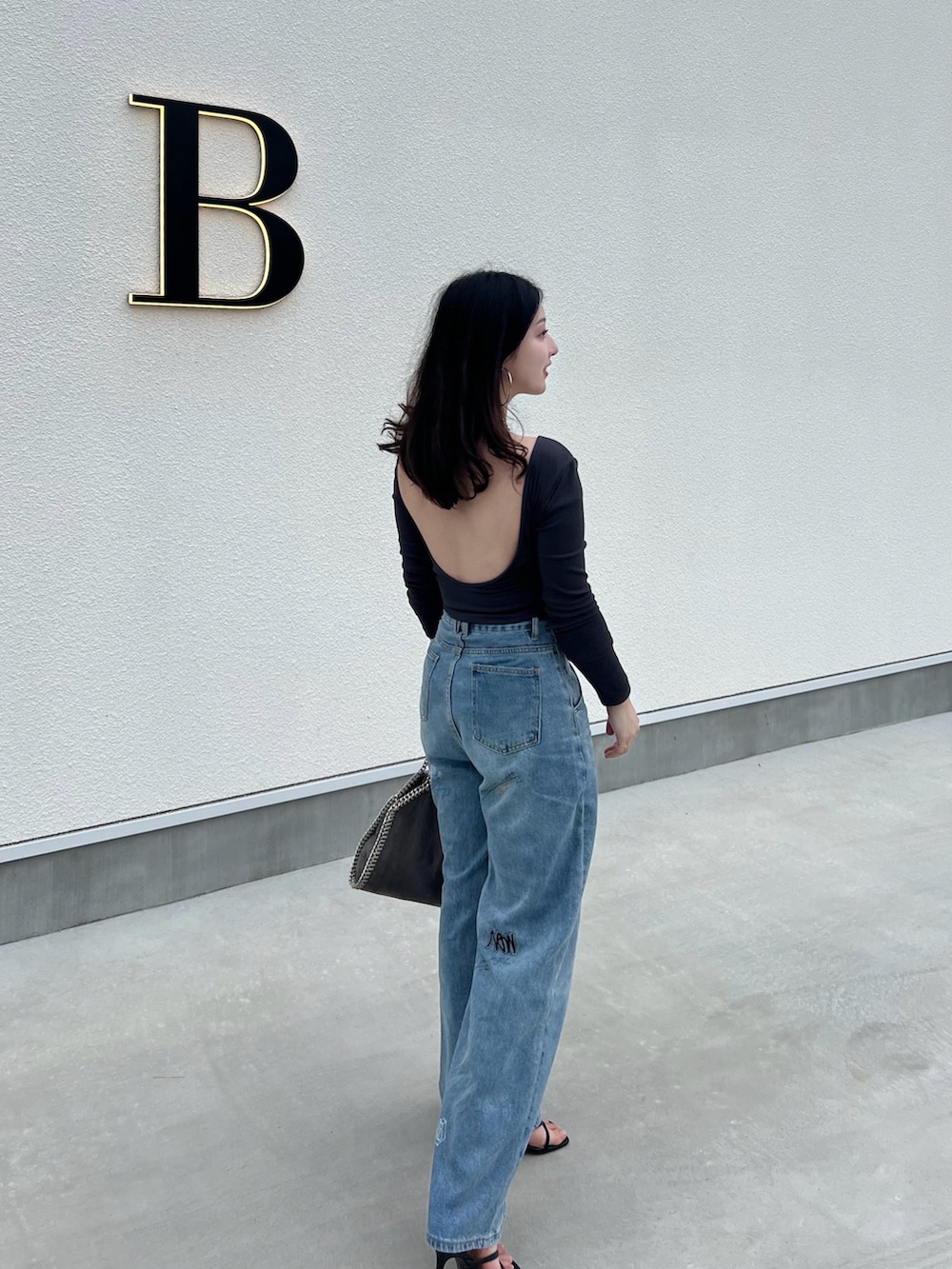 ブルー系のデニムパンツ、グレー系のTシャツ/カットソー、ブラック系のサンダルを着用したレディースの春コーディネートの2枚目の写真